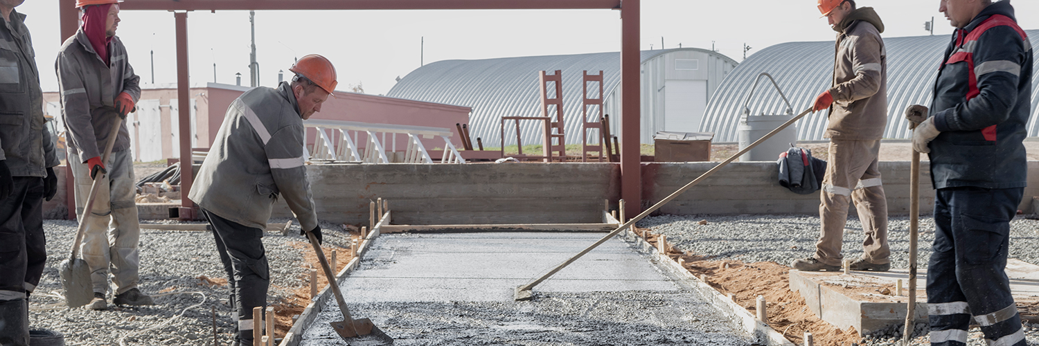 Pouring cement or concrete with a concrete mixer truck, construction site with a reinforced grillage foundation. Workers settle and level the concrete in the foundation